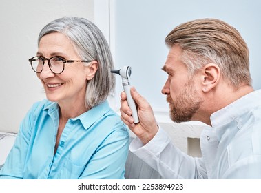 Otolaryngologist doctor checking mature woman's ear using otoscope or auriscope at ENT clinic. Hearing exam - Powered by Shutterstock