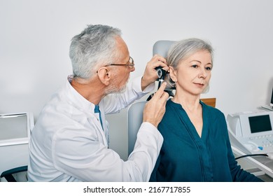 Otolaryngologist doctor checking senior woman's ear using otoscope or auriscope at hearing center. Audiology - Powered by Shutterstock