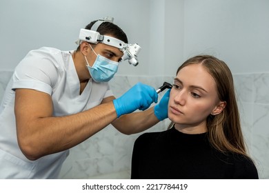 An Otolaryngologist Examines The Auricle. Hearing Clinic. An ENT Doctor With Instruments In A Mask And Gloves Examines The Patient's Ear.