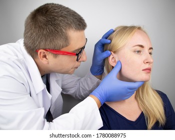 An Otolaryngologist Examines The Ear Of A Girl Who Complains Of Pain. Pain Relief And Treatment Concept. Inflammation Of The Ear Canal Or Eardrum