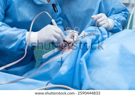 Otolaryngologist performs tonsillectomy, removal of tonsils, ENT. septoplasty, maxillofacial surgery.An array of medical instruments and hoses is visible, indicating a sterile surgical environment. 