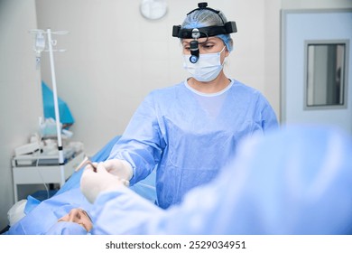 Otolaryngologist surgeon works with an assistant in an operating room - Powered by Shutterstock