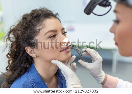 Otolaryngology concept. Positive woman otorhinolaryngologist checking nose with otoscope of his patient at hospital. Nasal congestion, sinusitis, allergy concept. Female patient at modern ENT clinic.