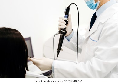 The otolorinologist conducts manipulations to investigate the diseases of the nose with the help of endoscope and a probe. Hands in gloves, on the head a sterile mask and a doctor's medical flashlight