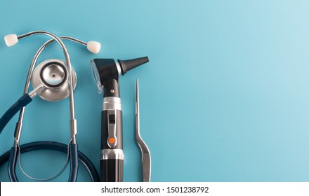 Otoscope with stethoscope on blue background.