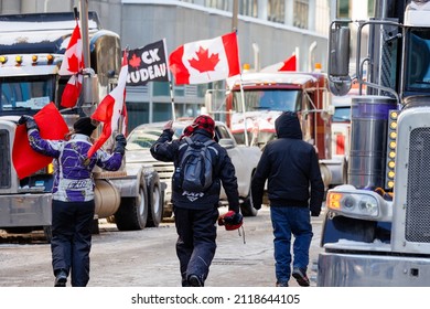 Ottawa, Canada – February 5 2022: Supporters of the Freedom Convoy walk through a street lined with transport trucks and encourage the truckers