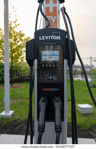 Ottawa\
Canada May 21 2022: Leviton electric vehicle charging station at a\
parking lot. Renewable energy, soaring gas prices, zero emission,\
no pollution, carbon tax, green planet\
concept.