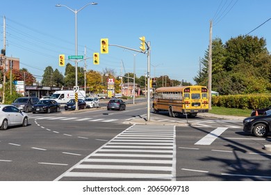 Ottawa, Canada- October 6, 2021: Crossroads of Baseline and Greenbank roads in Ottawa city with traffic lights, crosswalk, school bus and cars on street in fall season on sunny day