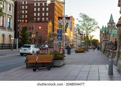Ottawa, Canada - September 19, 2021: Wellington street view with benches, cars on road and walking people in downtown of Ottawa near Parliament in evening.