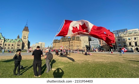 Ottawa Ontario Canada April 30 2022. Rolling Thunder Veteran Biker Protest And Demonstration Crowd With A Person Waving A Large Canadian Flag At The Canadian Parliament Hill.