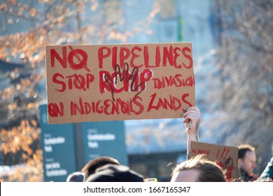OTTAWA, ONTARIO, CANADA - FEBRUARY 17, 2019: A hand raises a sign saying "No Pipelines" and "Stop RCMP Invasion on Indigenous Lands" at a protest against Canadian relations with First Nations peoples.