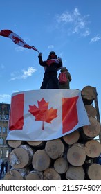 Ottawa Ontario Canada January 29 2022. Freedom Convoy 2022 Protester Waving A Canadian Flag Atop A Log Truck On Wellington Street Near The Canadian Parliament Hill.