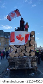 Ottawa Ontario Canada January 29 2022. Freedom Convoy 2022 Protester Waving A Canadian Flag Atop A Log Truck On Wellington Street Near The Canadian Parliament Hill.