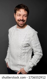 Ottawa, Ontario/Canada - January 3,2019: Studio Portrait Of A 35 Year Old Caucasian Man Wearing A White Sweater And Smiling. He Is Looking Away From The Camera And The Backdrop Is Black.