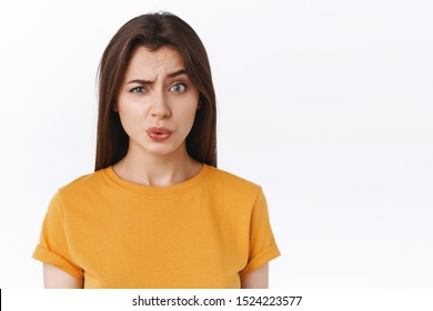 Ouch it probably hurts. Pity good-looking modern brunette woman in yellow t-shirt cringe and grimace as seeing someone got punched in face, folding lips and look uneasy camera, white background - Shutterstock ID 1524223577