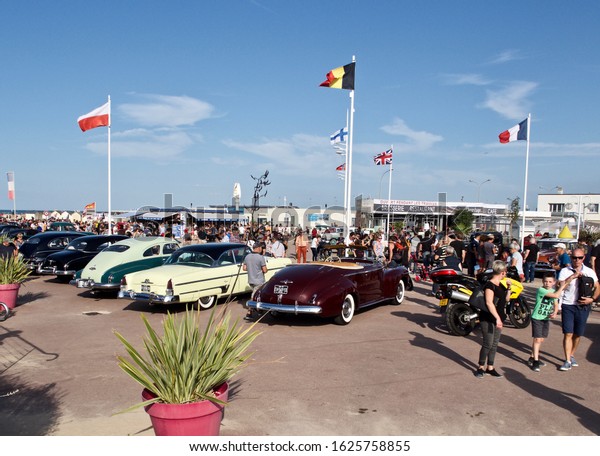 Ouistreham, France September 21, 2019. Fans,\
people walking on the street next to each other are playing sports\
competitions, racing of old cars and motorbikes. A beautiful sunny\
day in Calvados