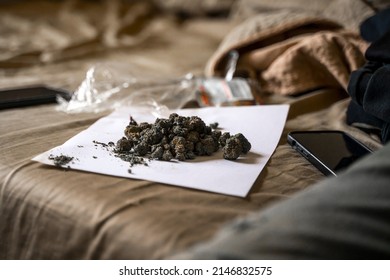 An ounce of cherry cannabis flower on a bed.