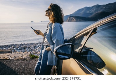 oung woman traveler in a hat standing by her car during summer sea holiday - Powered by Shutterstock