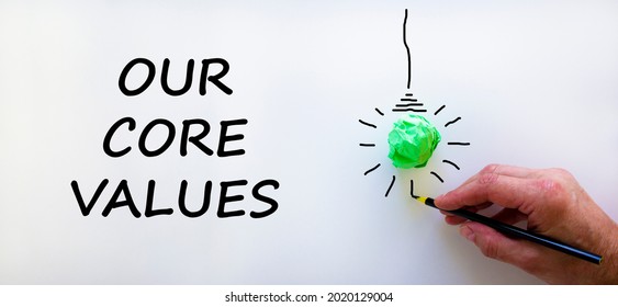 Our Core Values Symbol. Businessman Writing Words 'Our Core Values', Isolated On Beautiful White Background. Light Bulb Icon. Business And Our Core Values Concept. Copy Space.