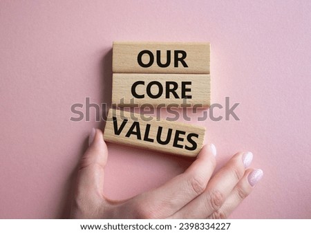 Our core values symbol. Concept words Our core values on wooden blocks. Beautiful pink background. Businessman hand. Business and Our core values concept. Copy space.