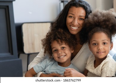 Our favorite teacher! Portrait of happy friendly african family millennial mother and two diverse children, talented black female tutor babysitter looking at camera posing with beloved pupils wards