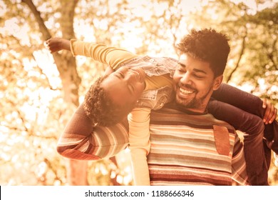 Our Funny Time. Happy African American Father In Park Carrying His Daughter On Shoulders.