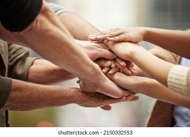 Our passion and dedication will take us to the top. Closeup shot of a group of unrecognisable people joining their hands together in a huddle. - Shutterstock ID 2150332553