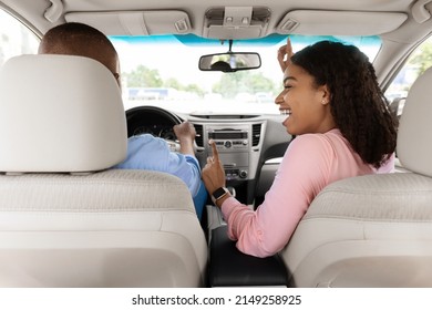 It's Our Song. Back Rear View Portrait Of Cheerful Positive Black Guy Driving New Automobile, Excited Lady Dancing To Music And Singing, Enjoying Favorite Road Playlist, Two People Going On Vacation