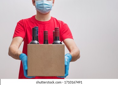  Ourier Wearing Protective Mask And Gloves Holding Box With Bottles Of Wine. Safe Online Wine Store Delivery During Quarantine.