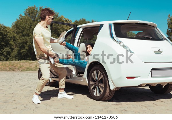 Out of car. Funny husband\
feeling amazing while taking his woman out of the car for having\
picnic