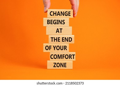 Out from comfort zone symbol. Wooden blocks with words Change begins at the end of your comfort zone. Beautiful orange background, copy space. Businessman hand. Business out from comfort zone concept.