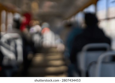 Out Of Focus Bus Interior With Multiple Seated Silhouettes Along Aisle Creating Abstract Pattern Of Light And Shadow During Daytime Commuter Journey On Public Transport.