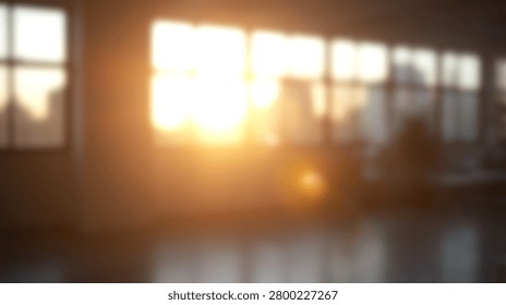 Out of focus empty office space with warm sunlight flare shining through large windows at sunset