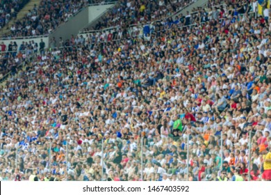 Out Of Focus, Not Sharp Sport Background - Spectators At Stadium. Crowds Of Fans In Stands Of Football Stadium During Match Tribune With Fans. Stands With Football Fans