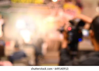 out of focus video and camera operators on tripods recording video and photos at an event
