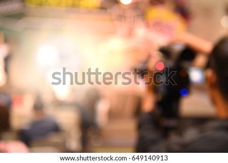 out of focus video and camera operators on tripods recording video and photos at an event