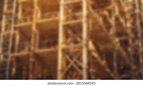 Out of focus view of complex metal scaffolding and industrial framework with warm lighting at a construction site.