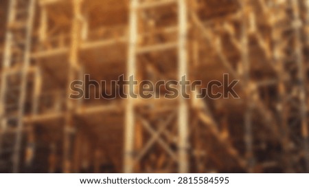 Out of focus view of complex metal scaffolding and industrial framework with warm lighting at a construction site.
