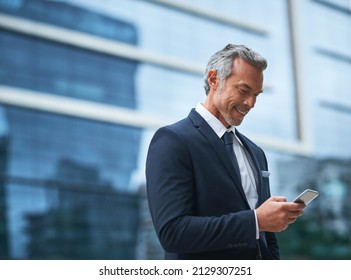 Out of the office but they still contacting me. Shot of a handsome mature businessman in corporate attire using a cellphone outside during the day. - Shutterstock ID 2129307251