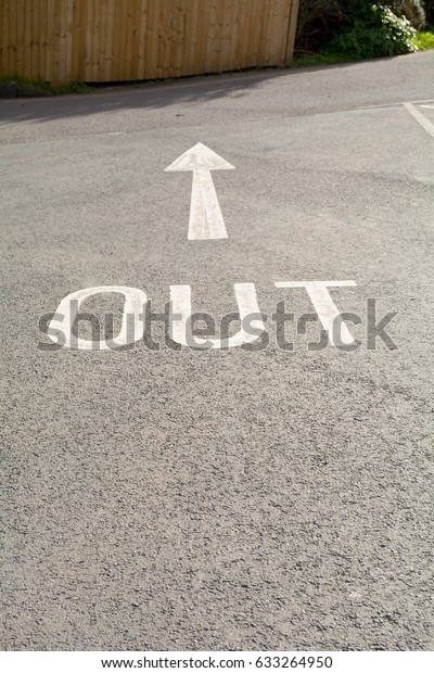 Out sign with direction arrow painted on tarmac in\
car park