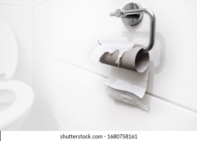 Out Of Stock, No More Toilet Paper. Last Piece Of Paper On A Roll In A Clean And Empty White Bathroom. Panic, Fear And World Wide Shopping Crisis Related To The Outbreak Of The COVID-19 Coronavirus.