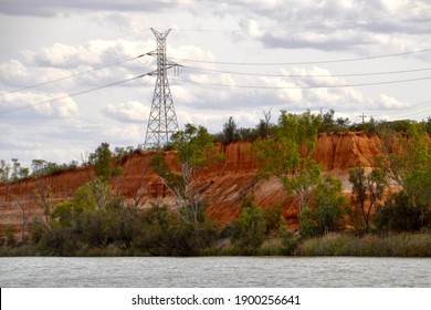 Outback Australia Power Pylon On Red Dirt Cliffs With Trees Above The Murray River On A Cloudy Day