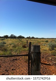 An Outback Fence, Stretching For Miles Across A Red, Outback Landscape.