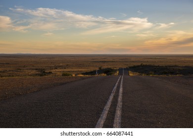 Outback Road Disappearing Into Wide Open Desert Landscape At Sunset Near Silverton In New South Wales, Australia.