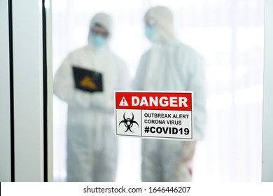 Outbreak Alert Coronavirus COVID 19, COVID 19 Signage In Front Of Control Area With Doctors In Personal Protective Equipment Inside.