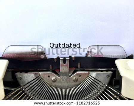 OUTDATED, word title heading typewritten in black on white paper on vintage manual typewriter machine, suitable concept for obsolete technology, business, ideas, policies, objects
