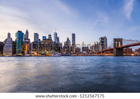 Outdooors view on NYC New York City Brooklyn Bridge Park by east river, cityscape skyline at sunset, dusk, twilight, blue hour, dark night, skyscrapers, buildings, waves, blurred, blur, blurry boat