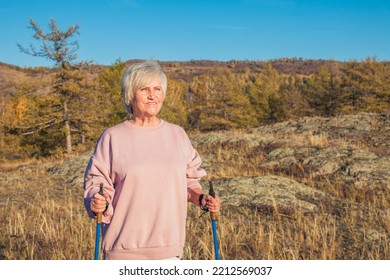 Outdoor Activities, People And Vacations Concept. Attractive Short Haired Middle Aged Woman In Activewear Hiking In Forest Using Poles For Nordic Walking, Doing Aerobic Workout, Enjoying Nature
