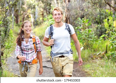 Outdoor Activity Couple Hiking - Happy Hikers Walking In Forest. Hiker Couple Laughing And Smiling. Multiracial Group, Caucasian Man And Asian Woman On Big Island, Hawaii, USA.