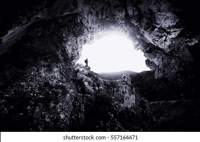 Outdoor adventure. Man exploring huge underground cave entrance, dark majestic landscape - Powered by Shutterstock